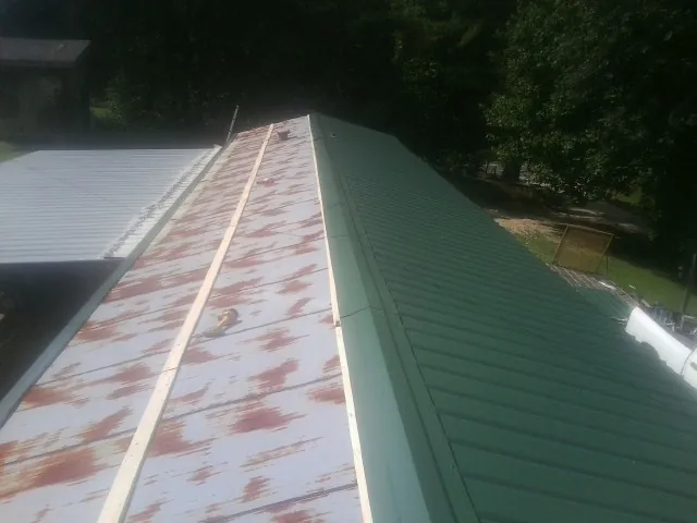 Old rusted panels beside newly installed green metal roofing — Wind Damage Roof Repair by Roofing Brothers in Ringoes