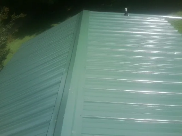 New green metal panels meeting at the ridge of a roof — Flat Roof Repair work by our crew in Ringoes