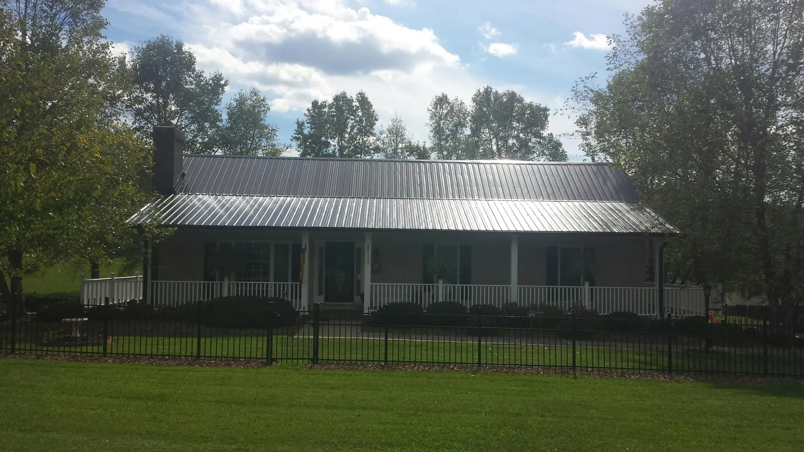 Gray metal roof on a brick ranch with a full width front porch — Gutter Guard Installation work by our crew in Ringoes