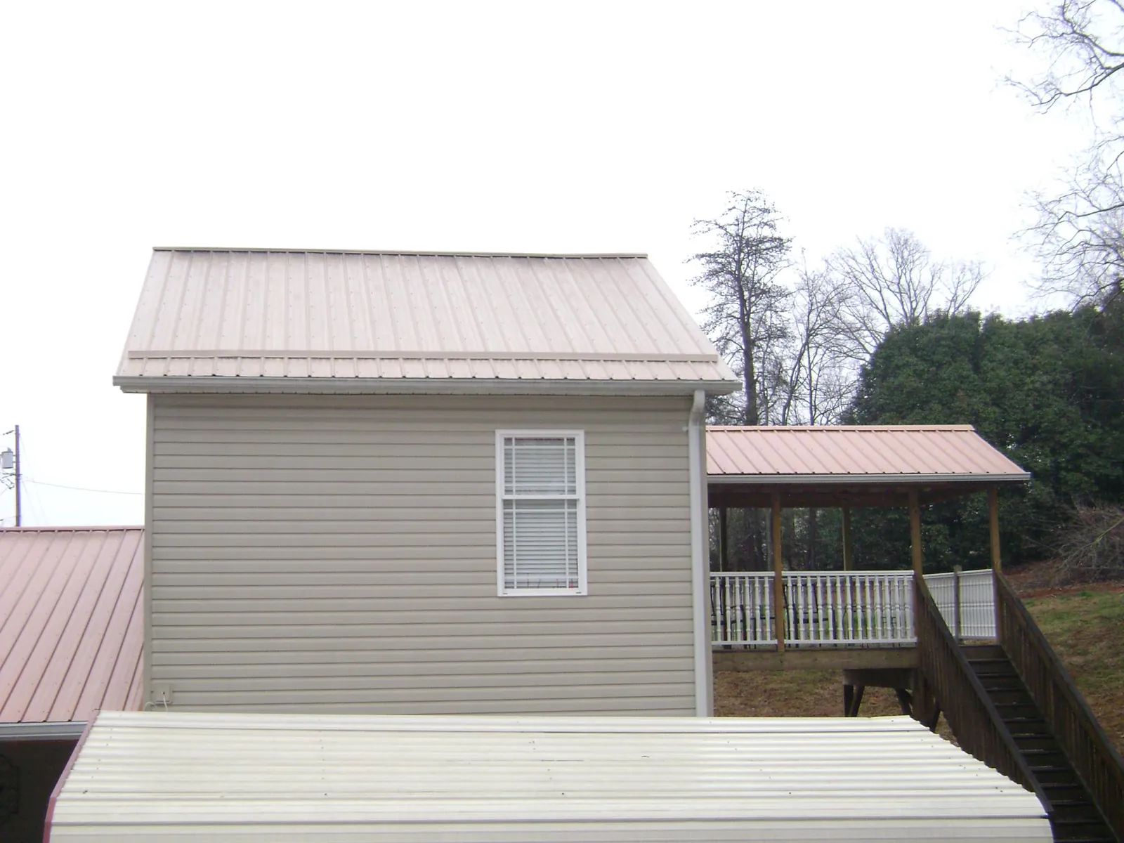 Tan metal roofs on a two story addition and attached porch, from a Roof Replacement job in Ringoes