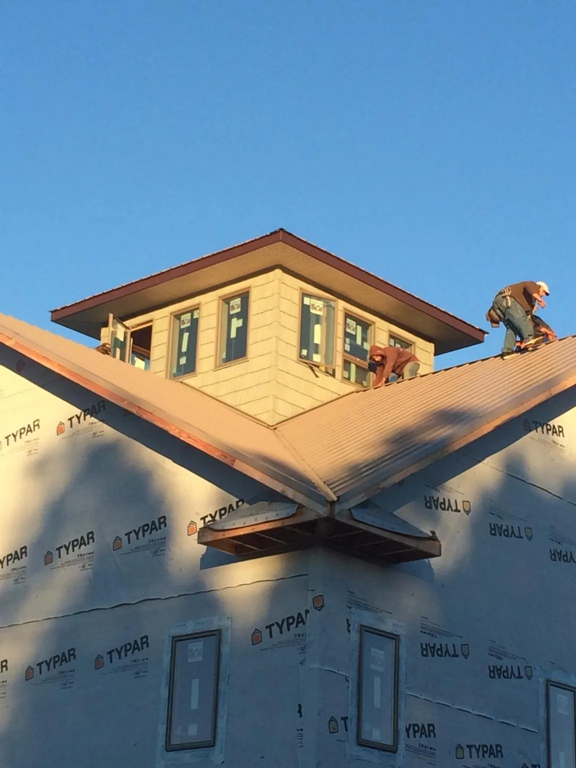 Roofers working around a rooftop cupola on a new metal roof at sunset — Roof Waterproofing in Ringoes by Roofing Brothers
